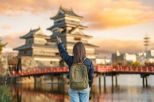 Woman tourist Visiting in Matsumoto, happy Traveler sightseeing Matsumoto Castle or Crow castle. Landmark and popular for tourists attraction in Matsumoto, Nagano, Japan. Travel and Vacation concept photo