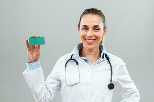 Portrait of beautiful female doctor holding business card. photo