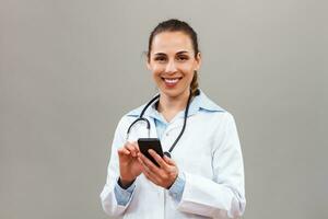 Beautiful female doctor texting messages on mobile phone. photo