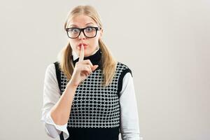 Nerdy woman with a finger on her lips photo