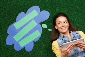 Woman thinking with thought bubble while using digital tablet photo