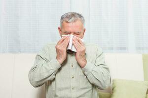 Senior man is sneezing into handkerchief. photo