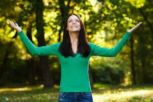 Happy woman with arms outstretched enjoys in park photo