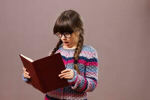 Surprised little nerdy girl holding book photo