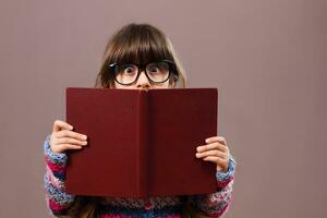 Little nerdy girl hiding behind a book photo