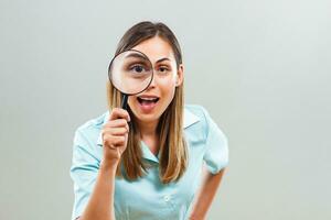 Excited nurse looking through loupe. photo