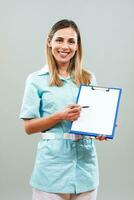 Beautiful nurse is holding clipboard and showing document with pen. photo