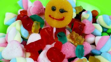 Piles of various kinds of sweets and candies with a focus on the smiling candy video