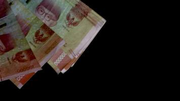 räkning 100 000 rupiah förbi hand på svart bakgrund. indonesiska valuta, betyder av betalning i indonesien video