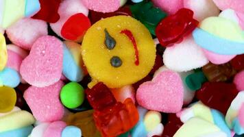 Piles of various kinds of sweets and candies with a focus on the smiling candy video