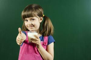Little girl with glass of milk showing thumb up photo