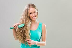 Young woman brushing her gorgeous long blonde hair. photo