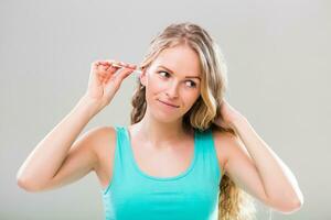 Beautiful young woman cleaning ears on gray background. photo