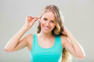 Beautiful young woman cleaning ears on gray background. photo