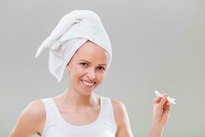 Beautiful young woman cleaning ears on gray background. photo