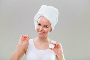 Beautiful young woman using dental floss on gray background. photo