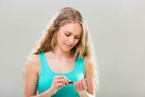 Beautiful woman using nail file on gray background. photo