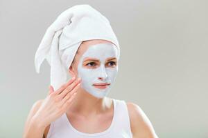 Portrait of young woman with facial mask on gray background. photo