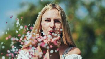 A girl blows a multicoloured paper confetti out of her hands. photo