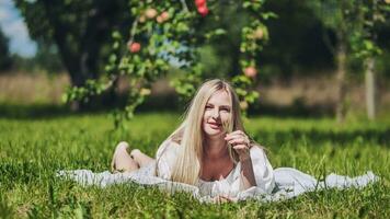 A blonde girl lies in a clearing in an apple orchard. photo