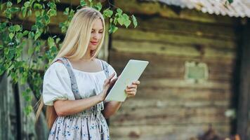 Village Slavic girl flipping a tablet in the countryside. photo