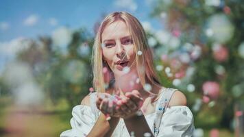 A girl blows a multicoloured paper confetti out of her hands. photo