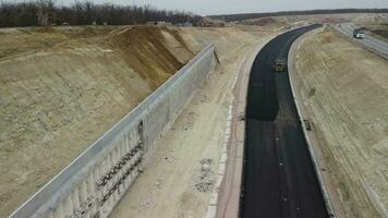 lavoratori rafforzare il pendenza al di sopra di il nuovo strada. strada costruzione nel progresso su pendenza natura canyon. infrastruttura sviluppo e la logistica. aereo fuco tiro video