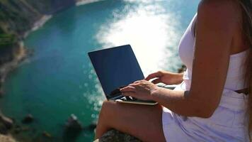 Freelance, digital nomad. Well looking middle aged woman typing on laptop keyboard outdoors on terrace with beautiful sea view. Close up woman hands writing on computer. Travel and holidays concept. video