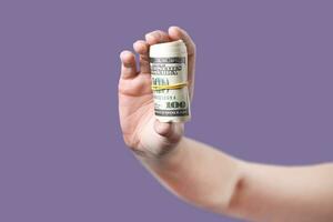 Woman's hand shows rolled up money violet background photo