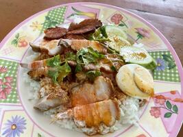 crispy pork with vegetables and rice on plate on table, thai food photo