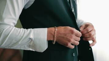 Male hands fasten a button on a jacket. Close up. The groom fastens his jacket with his hands. A stylish man in a suit fastens his buttons, getting ready to go out. video