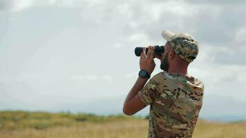 uma militares homem examina a área com binóculos. guerra dentro Ucrânia. video