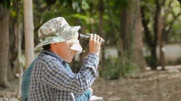 joven asiático Niños son utilizando un binocular a Estar atento para aves y animales en un local parque, suave y selectivo atención foto