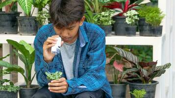 Young boy is using a white small microscope to inspect and to study plant in a tiny flowerpot in botanical garden, soft and selective focus photo