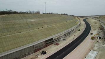 Workers reinforce the slope over the new road. Road construction in progress on slope nature canyon. Infrastructure development and logistics. Aerial drone shot video