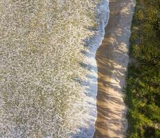 Aerial top view of sandy beach with stunning waves. photo