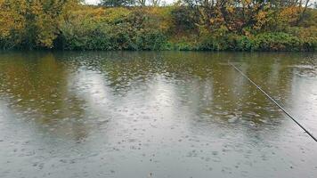 Angeln auf das Fluss im regnerisch Wetter. Landschaft von wolkig Wetter auf das Fluss Bank. Regentropfen fallen in das Wasser. video