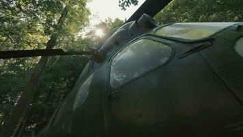 An old military helicopter in the forest, a view of the propellers through which the sun's rays shine. Close up video