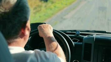 Masculin mains sur pilotage roue. le retour de le tête de un personnes âgées voiture chauffeur et une vue de le sien mains conduite le voiture hors route. video