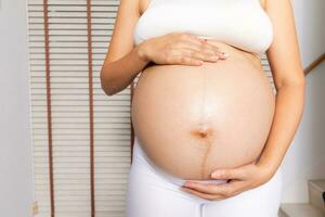 retrato de un embarazada mujer conmovedor su grande barriga cerca arriba, madre, el embarazo, personas y expectativa. mujer participación grande embarazada estómago foto