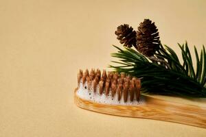 Toothbrush with toothpaste foam on a background of pine needles and cones. photo