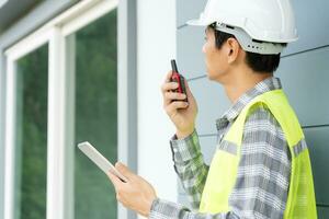 inspector or engineer is inspecting construction and quality assurance new house using a tablet. Engineers or architects or contactor work to build the house before handing it over to the homeowner photo