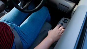 Hand pressing a car window lock button. driver is pressing buttons of window switches with remote control inside modern car, opening and lowering glass. photo