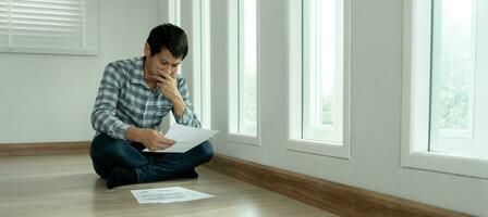 Stressed and headache asian man with large bills or invoices no money to pay to expenses and credit card debt. shortage, Financial problems, mortgage, loan, bankruptcy, bankrupt, poor, empty wallet photo