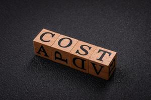 The inscription cost in wooden cubes on a dark concrete background photo