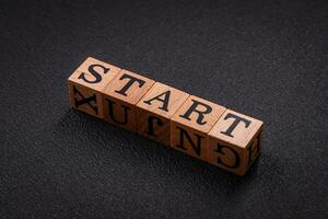 The inscription start on wooden cubes on a dark concrete background photo