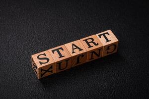 The inscription start on wooden cubes on a dark concrete background photo