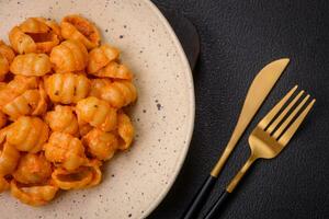 Delicious fresh pasta with pesto sauce, salt, spices and herbs on a ceramic plate photo