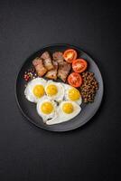 Delicious nutritious breakfast of fried quail eggs, bacon, legumes and cherry tomatoes photo