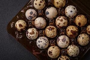 Raw quail eggs in a plastic box on a dark concrete background photo
